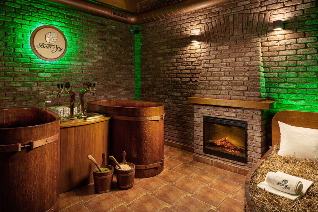 Într-un spa cu bere, se văd două căzi cu bere și două dozatoare de bere, dar și un pat cu paie pentru relaxare și un șemineu.